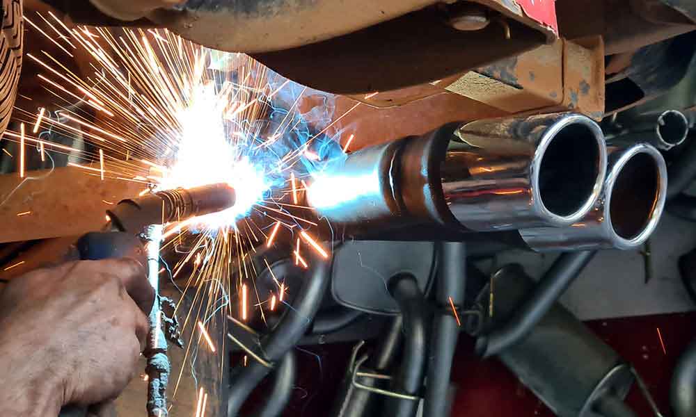 Exhaust tailpipes being welded during automotive repair
